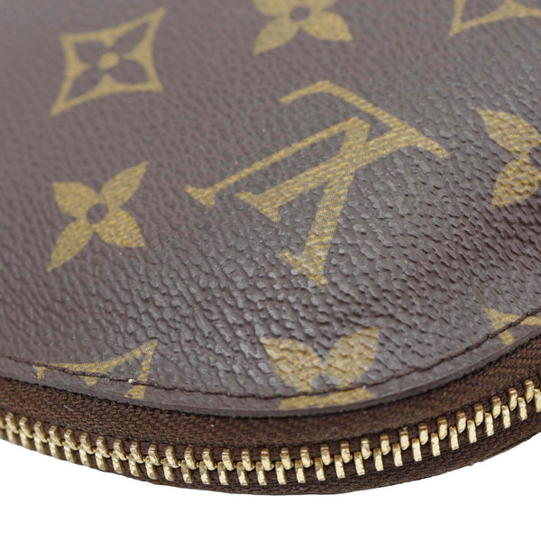 Close-up of a brown leather pouch with gold zipper and logo pattern
